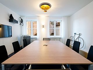 An dem großen Besprechungstisch des Meetingraums der FOX LOUNGES München ist ausreichend Platz für mehrere Personen