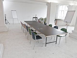 An einer langen Tafel der FilmFabrique Hamburg finden Teilnehmer eines Workshops oder eines Seminars Platz und haben verschiedene Materialien zu Verfügung 