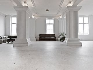 Möchten Sie sich auch auf das braune, gemütliche Sofa vor den hellen Fenstern des FilmFabrique Studios in Hamburg werfen?