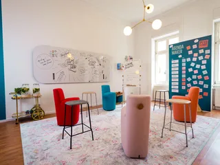 Ein Workshop-Raum, der mit bunten Möbeln, Whiteboards und Tafeln eingerichtet ist.