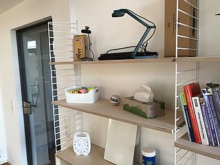 Kreativität anregend, sind im Regal Hilfsmittel, Bücher und interessante Gegenstände untergebracht. Alles im minimalistischen und modernen Design des movable.space in Oldenburg