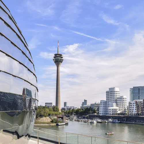 Düsseldorfer Fernsehturm und Medienhafen bei Tag mit blauen Himmel. Reflexion im Gebäude