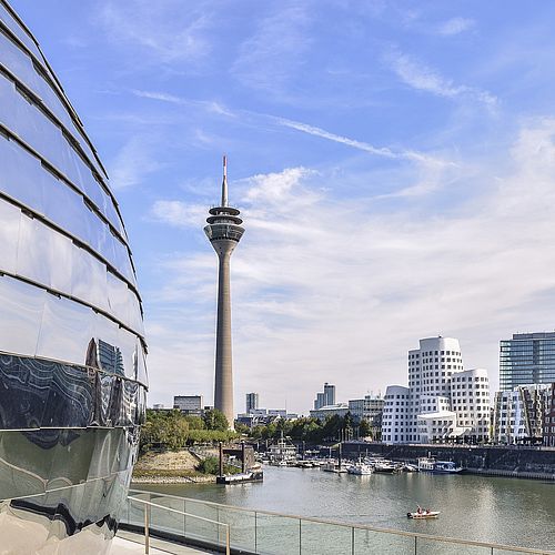 Düsseldorfer Fernsehturm und Medienhafen bei Tag mit blauen Himmel. Reflexion im Gebäude