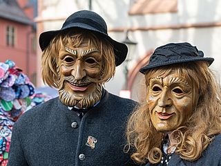 Die Fastnacht in Freiburg. Hierbei tragen die Menschen Masken und Perücken und lassen es und lassen es krachen.