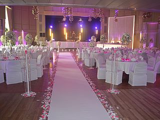 Mit großen Blumengestecken und weißer Bestuhlung wird das Potpourri in Bad Fallingbostel zur eleganten Hochzeitslocation
