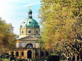 Der Friedhofs-Dom in Freiburg mit blauem Himmel und Bäumen