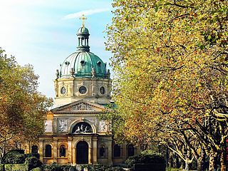 Der Friedhofs-Dom in Freiburg mit blauem Himmel und Bäumen