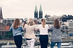 Das RAUMPERLE-Kernteam von hinten. Die Frauen auf einer Terrasse und schaut auf die Skyline von Bremen.