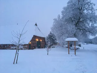 Eine Schneedecke liegt über dem Hof mit der Diele am See im Herzogtum Lauenburg